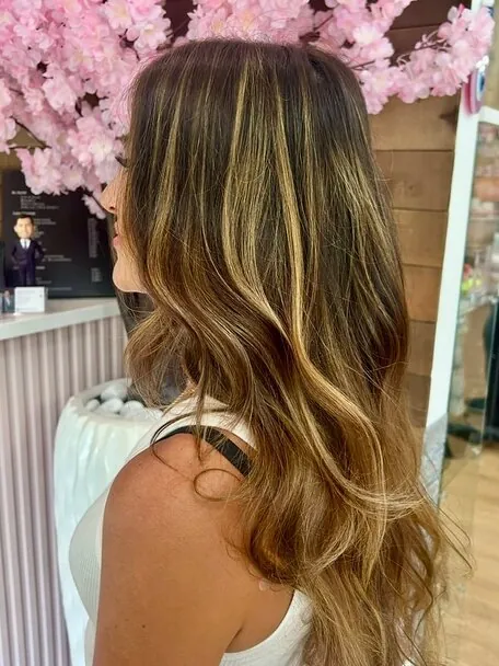 Hand-painted balayage falling from a dark root into sunlit ends