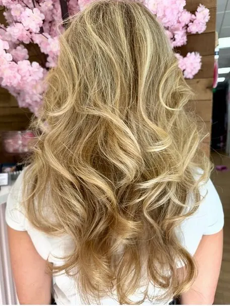 Long blonde hair with soft volume and curl, finished in the salon