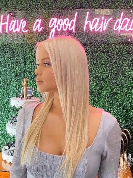 Long platinum blonde worn straight against the neon moss wall