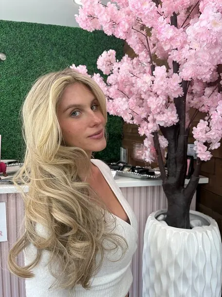 Loose blonde waves photographed by the salon's cherry blossom wall